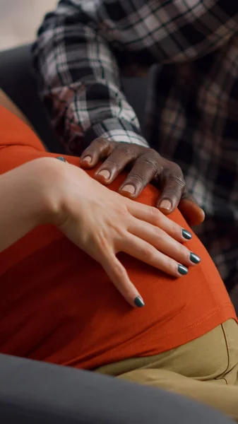 Close up de mãos inter-raciais de jovem casal na barriga — Fotografia de Stock