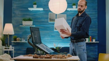 Mimar olarak çalışan adam maketi tutuyor ve dokunmatik ekran kullanıyor.