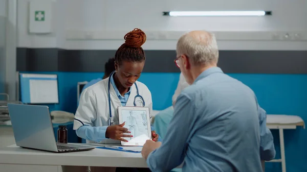 Spécialiste des soins de santé regardant tablette numérique avec vieux patient — Photo