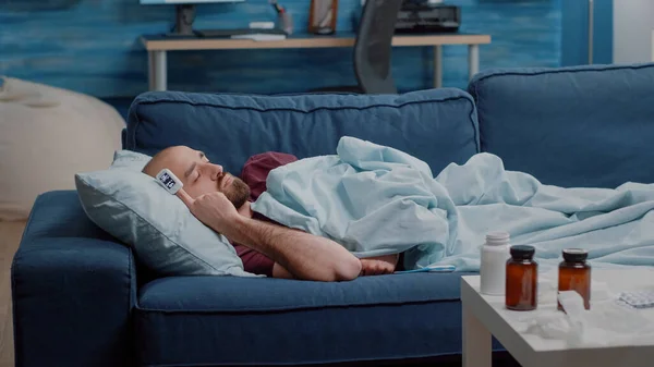 Nemocná osoba odpočívající na gauči s oximetrem na prstu — Stock fotografie