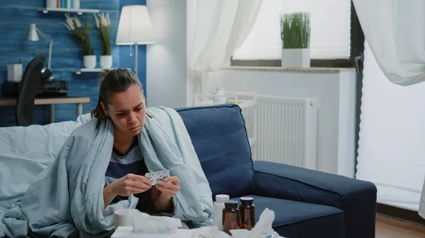 Donna malata guardando flacone di pillole e compresse con capsule — Foto Stock