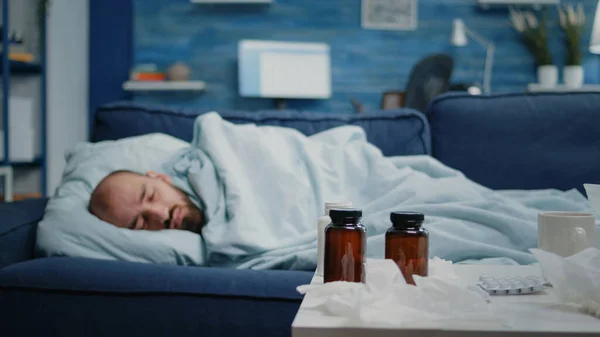 Mal hombre durmiendo en el sofá con manta mientras tiene frío — Foto de Stock
