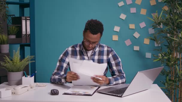 Νεαρός επιχειρηματίας που ταξινομεί τα οικονομικά διαγράμματα στα χαρτιά — Αρχείο Βίντεο
