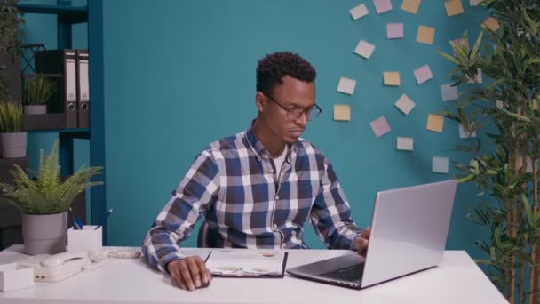 Young employee analyzing business charts on documents and laptop — Stock Video