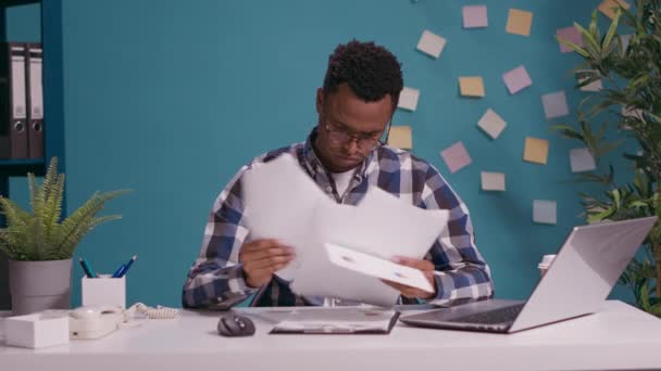 Une personne afro-américaine analyse des business charts sur des documents — Video