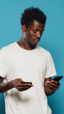 Genç adam akıllı telefondan online alışveriş için kredi kartı kullanıyor.