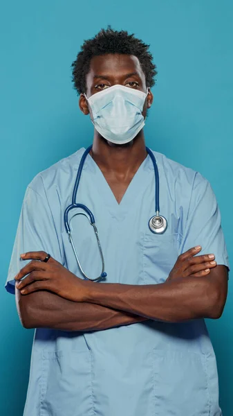 Homem enfermeira de pé com os braços cruzados ao usar máscara facial — Fotografia de Stock