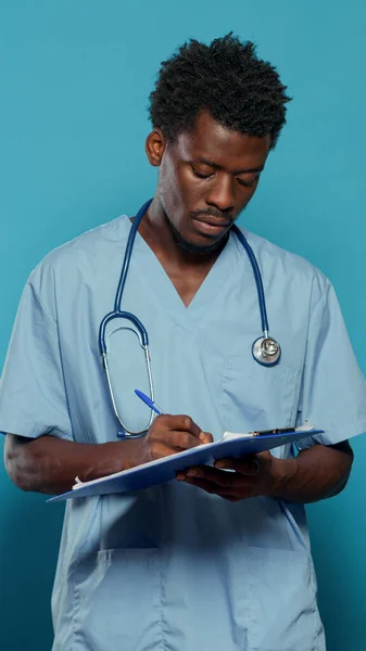 Homem trabalhando como enfermeiro e escrevendo em papel médico — Fotografia de Stock