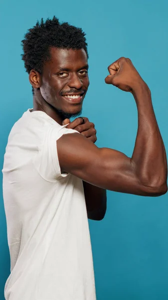 Athletic person flexing biceps muscles on camera in studio — Stock Photo, Image