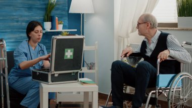 Tıbbi asistan yaşlı bir adama bir şişe hap veriyor.