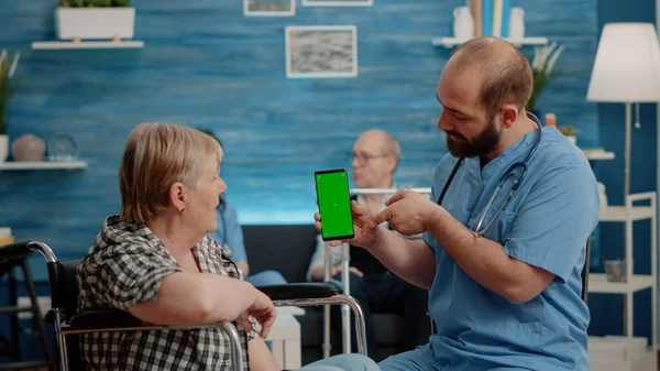 Sköterska vertikalt håller smartphone med grön skärm — Stockfoto