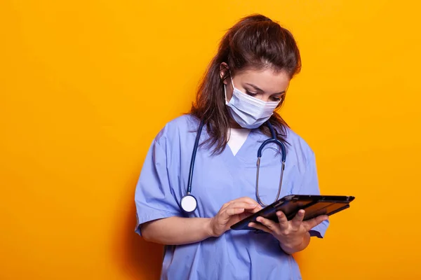 Assistente medico con maschera facciale utilizzando tablet digitale — Foto Stock