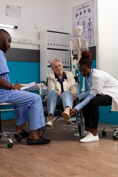 Paciente mayor geeting rodilla examinada durante la consulta de fisioterapia — Foto de Stock