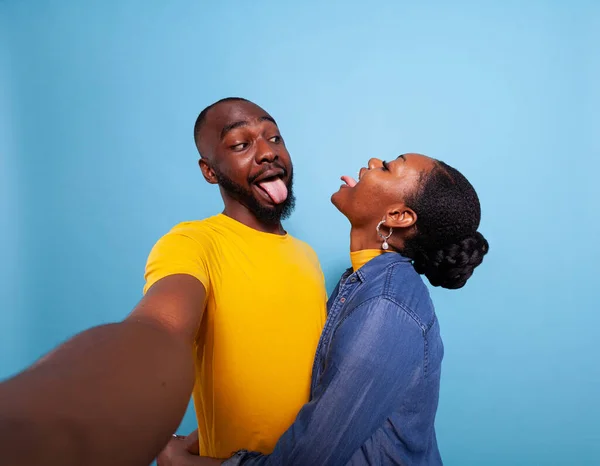 Silly lovers sticking tongue out at each other in front of camera — Stock Photo, Image