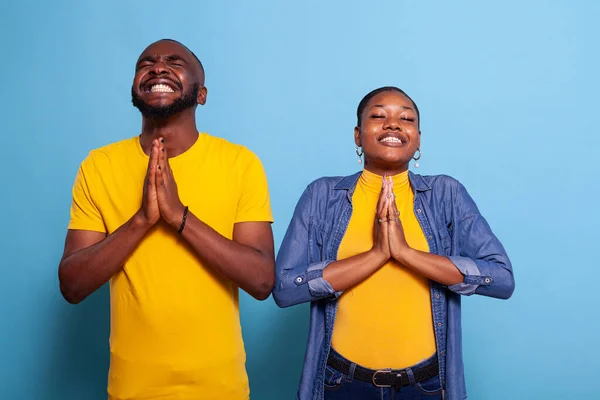 Religious couple praying to God with eyes closed and prayer hands — Stock Photo, Image