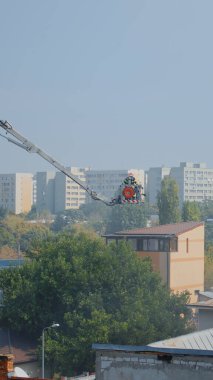 Platformdaki itfaiyeciler yangını söndürmek için çatıya çıkıyorlar.