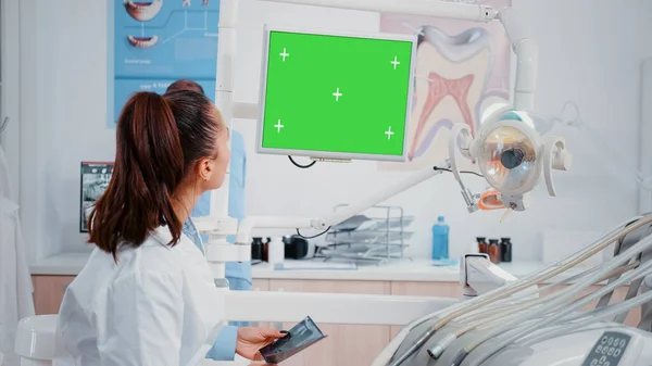 Dentista olhando para monitor com tela verde horizontal — Fotografia de Stock