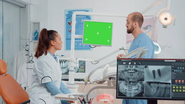 Dentista y asistente mirando la pantalla verde en el monitor —  Fotos de Stock