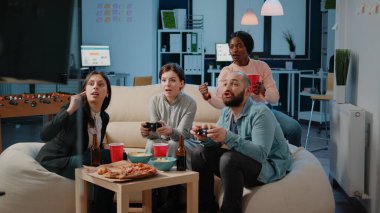 Oyun oynamak için joystickleri kullanan çeşitli iş arkadaşları grubu