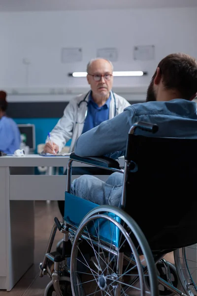Пациент, сидящий в инвалидной коляске встреча со специалистом во время осмотра визита, чтобы вылечить болезнь — стоковое фото