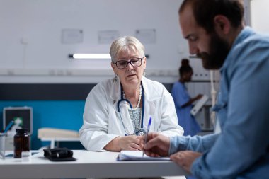 Tıbbi ziyaretteki hasta doktor ve randevu için kontrol dosyaları imzalıyor