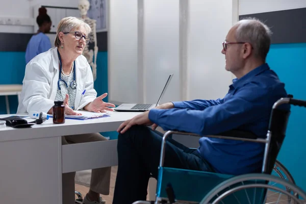 Лікар розмовляє з людиною з інвалідністю під час щорічного огляду відвідування медичного кабінету — стокове фото