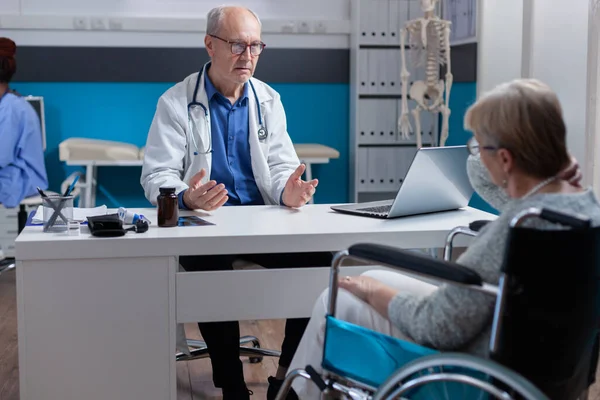 Fachärztin berät im Büro im Rollstuhl sitzende Patientin — Stockfoto