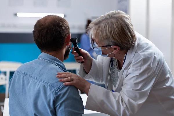 Крупним планом лікар, використовуючи отоскоп, щоб зробити консультацію вуха з пацієнтом — стокове фото