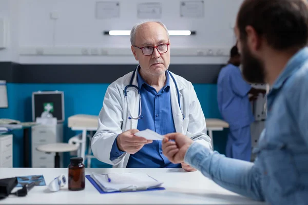 Il medico che somministra il file di prescrizione al paziente malato alla visita di controllo — Foto Stock