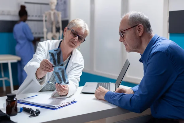 Ärztin und Mann analysieren Röntgenuntersuchungsergebnisse beim Vorsorgetermin — Stockfoto