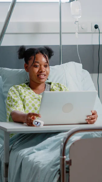 Giovane paziente che utilizza la videochiamata sul computer portatile moderno a letto — Foto Stock