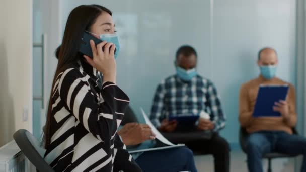 Азиатка разговаривает по телефону и ждет, чтобы присоединиться к собеседованию — стоковое видео