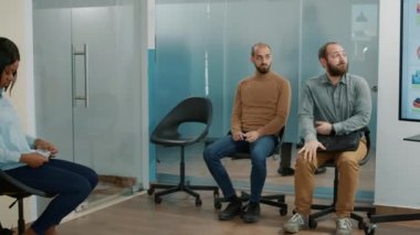 Hamile HR çalışanı ofis lobisinde bekleyen adaylara CV kağıtları veriyor.