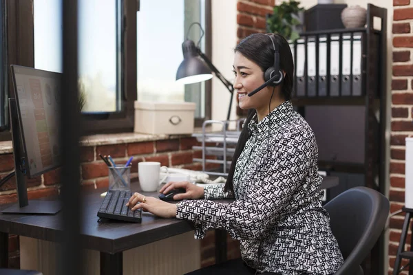 Call center smiling employee answering voicecall regarding customer complaint.