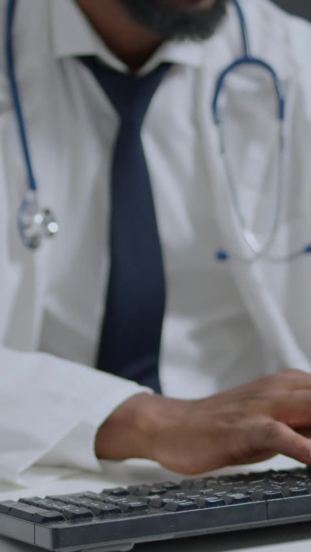 Porträtt av afrikansk amerikansk specialist läkare sitter vid skrivbordet skriva medicinering behandling — Stockvideo