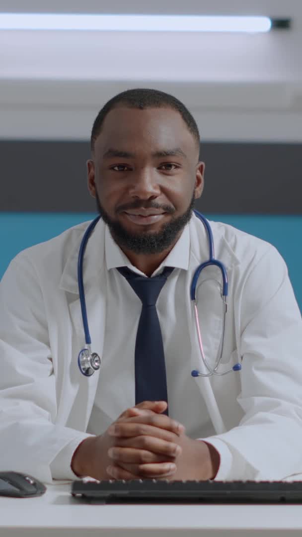 Pov de médico especialista afroamericano sentado en el escritorio en la oficina del hospital — Vídeos de Stock