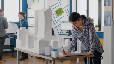 Bina modeli ve maketi tasarlamak için planlar hazırlayan kadın mimar.