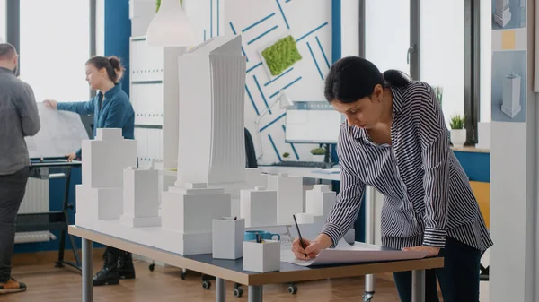 Kvinna arkitekt analysera ritningar planerar på bordet för att designa byggnad modell och maquette — Stockfoto