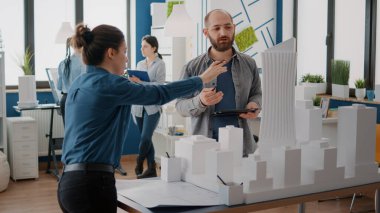 Tablet üzerinde inşaat planı yapmak için maquette ve bina modelini analiz eden çalışma arkadaşları.