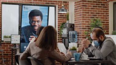 Yüz maskesi olan insanlar görüntüde uzak video konferansı kullanıyor