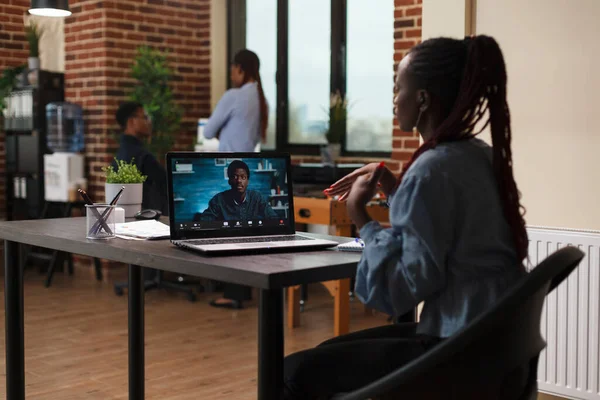 Zakenvrouw in remote videocall conferentie met executive officer tijdens het zitten aan het bureau in kantoorruimte. — Stockfoto