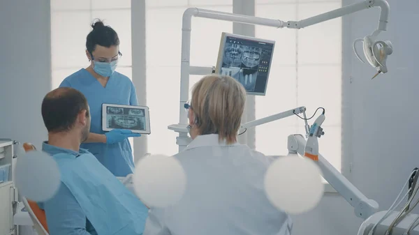 Dentist pointing at denture radiography on digital tablet — Foto Stock