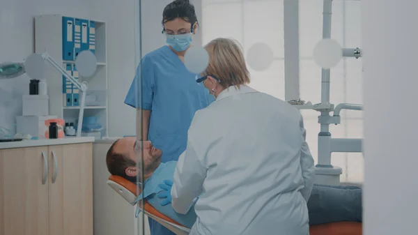 Медик и медсестра осматривают зубы после процедуры перорального ухода — стоковое фото