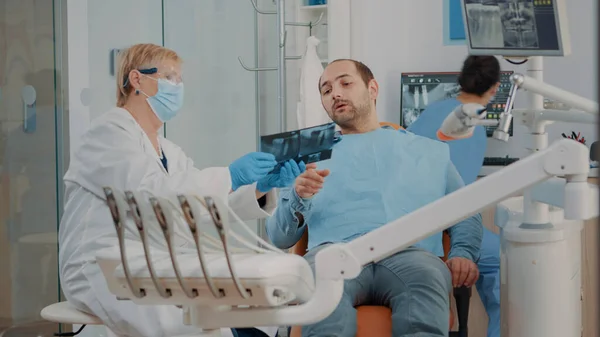 Стоматолог показывает пациенту рентгеновскую диагностику — стоковое фото