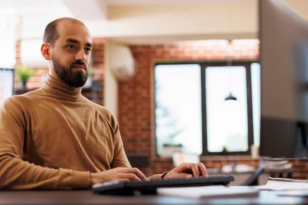 Empleado de la agencia de investigación sentado en la oficina mientras usa la computadora de trabajo para revisar la estrategia de marketing de proyectos de inicio. — Foto de Stock