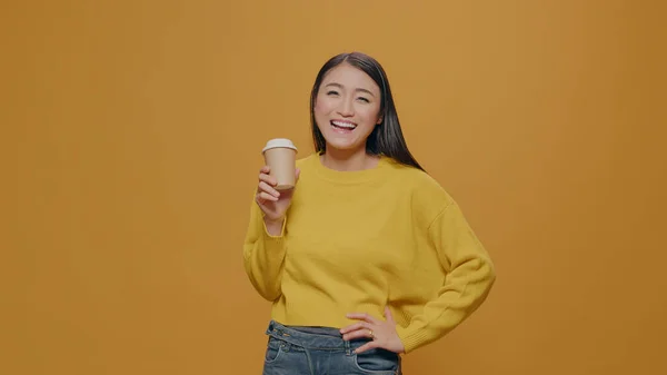 Kameranın önünde fincandan kahve içen Asyalı kadın. — Stok fotoğraf