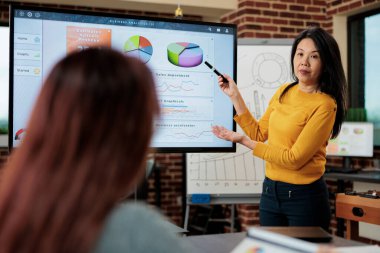 Girişimciye finansal grafikleri gösteren Asyalı yönetici