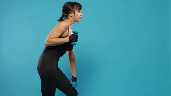 Mujer atlética usando mancuernas para hacer ejercicio en el estudio —  Fotos de Stock