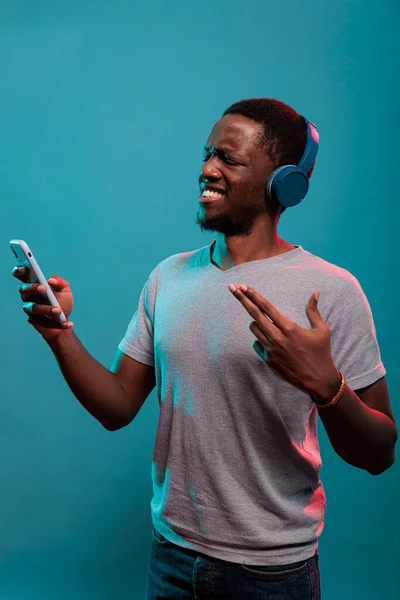 Podekscytowana osoba słuchająca muzyki na słuchawkach i korzystająca z telefonu — Zdjęcie stockowe