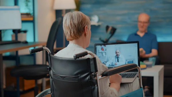 Pessoa aposentada em cadeira de rodas usando videoconferência — Fotografia de Stock